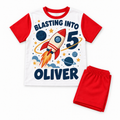 Red shorts birthday pyjamas with a rocket and planets, reading Blasting Into 5 and Oliver, on a white background.